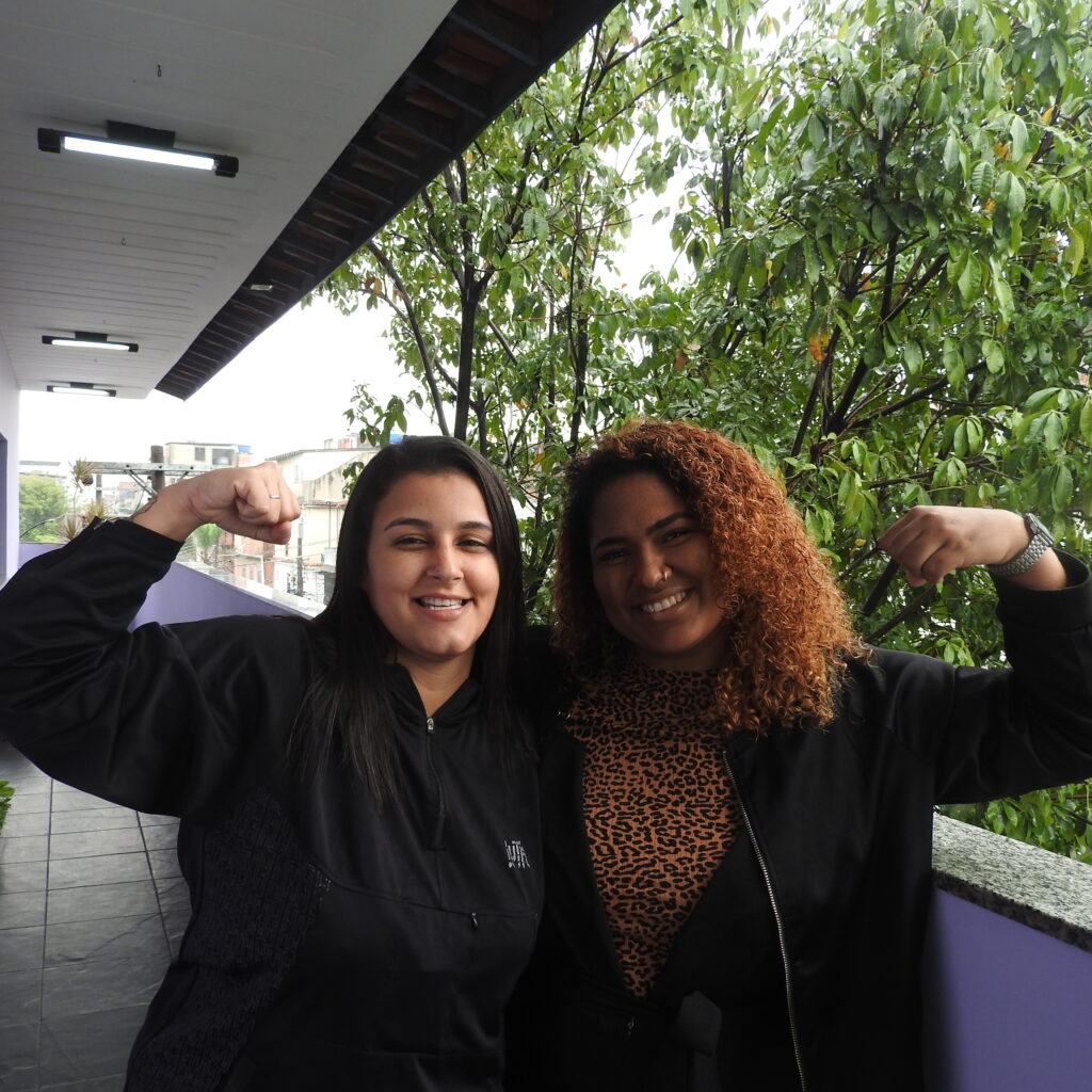 Duas mulheres erguem os braços em sinal de luta