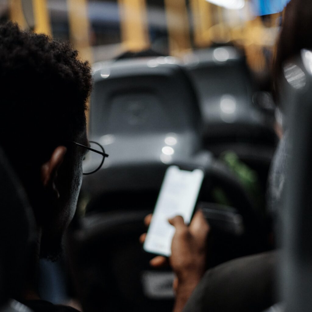 Homem negro com um celular na mão dentro de um ônibus