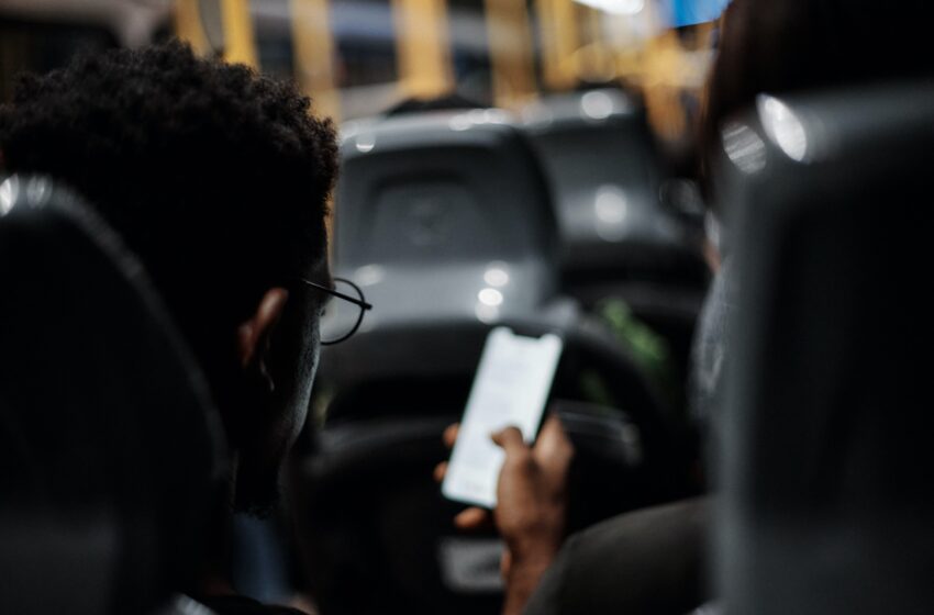 Homem negro com um celular na mão dentro de um ônibus